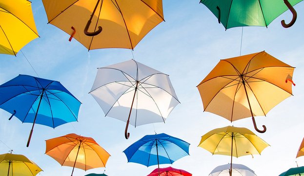 Parapluies de différentes couleurs volant dans un ciel bleu